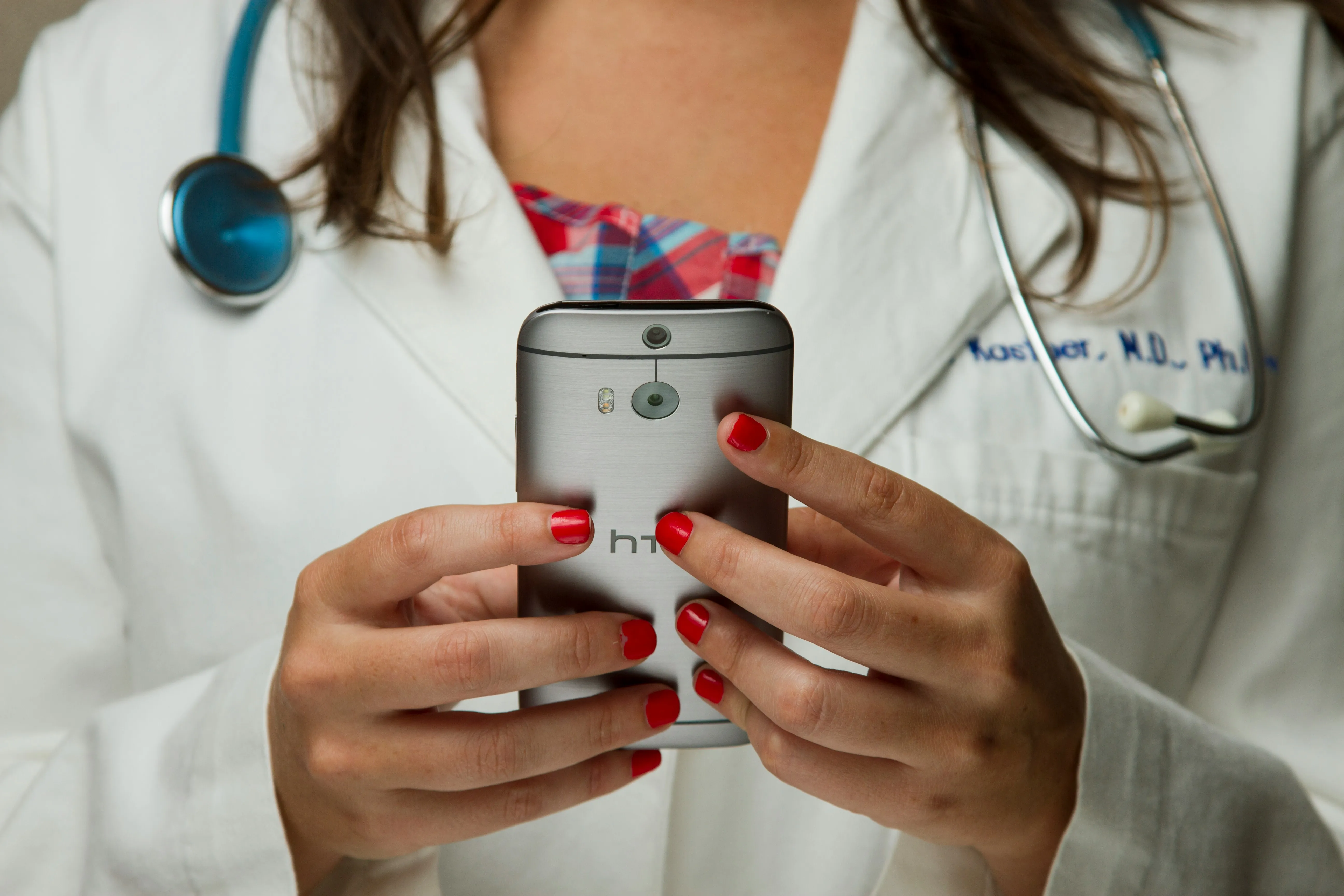 Clinician in a white lab coat holding a smartphone
