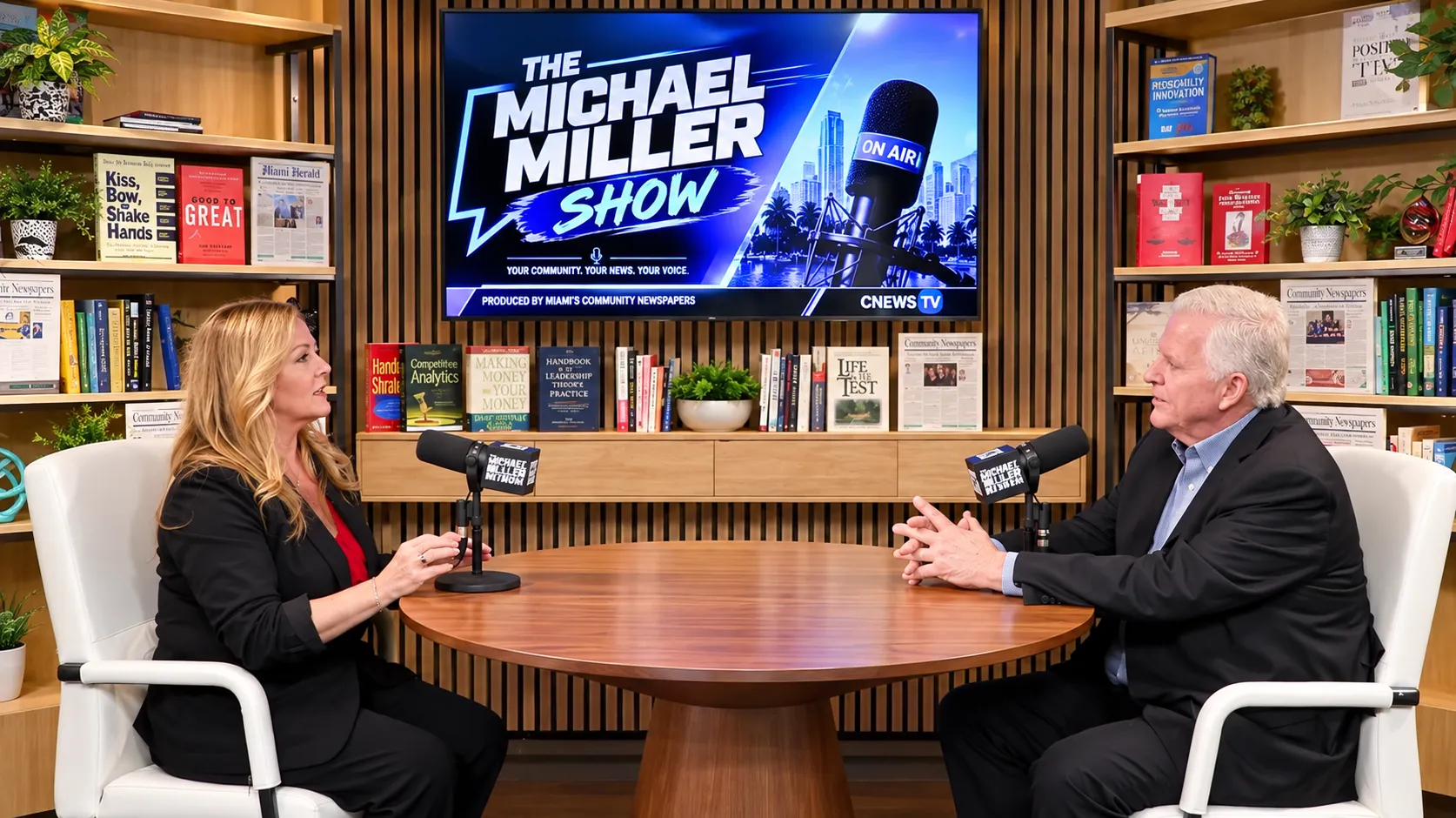 Two guests seated at a round table with microphones on The Michael Miller Show set, produced by Miami's Community Newspapers
